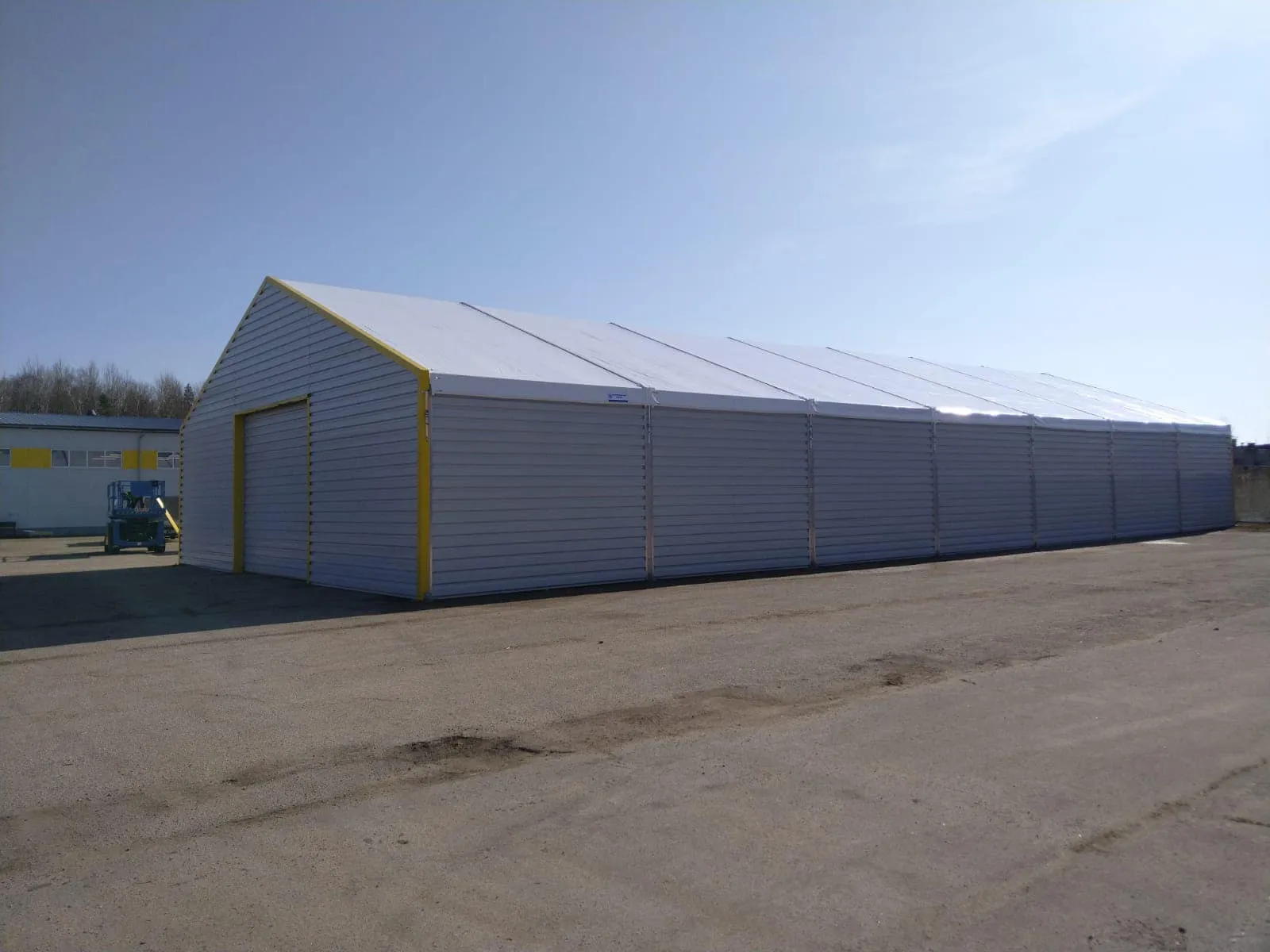 Jelgavas angārs ar T-35 skārda sienām un baltu PVC jumtu uz asfalta laukuma