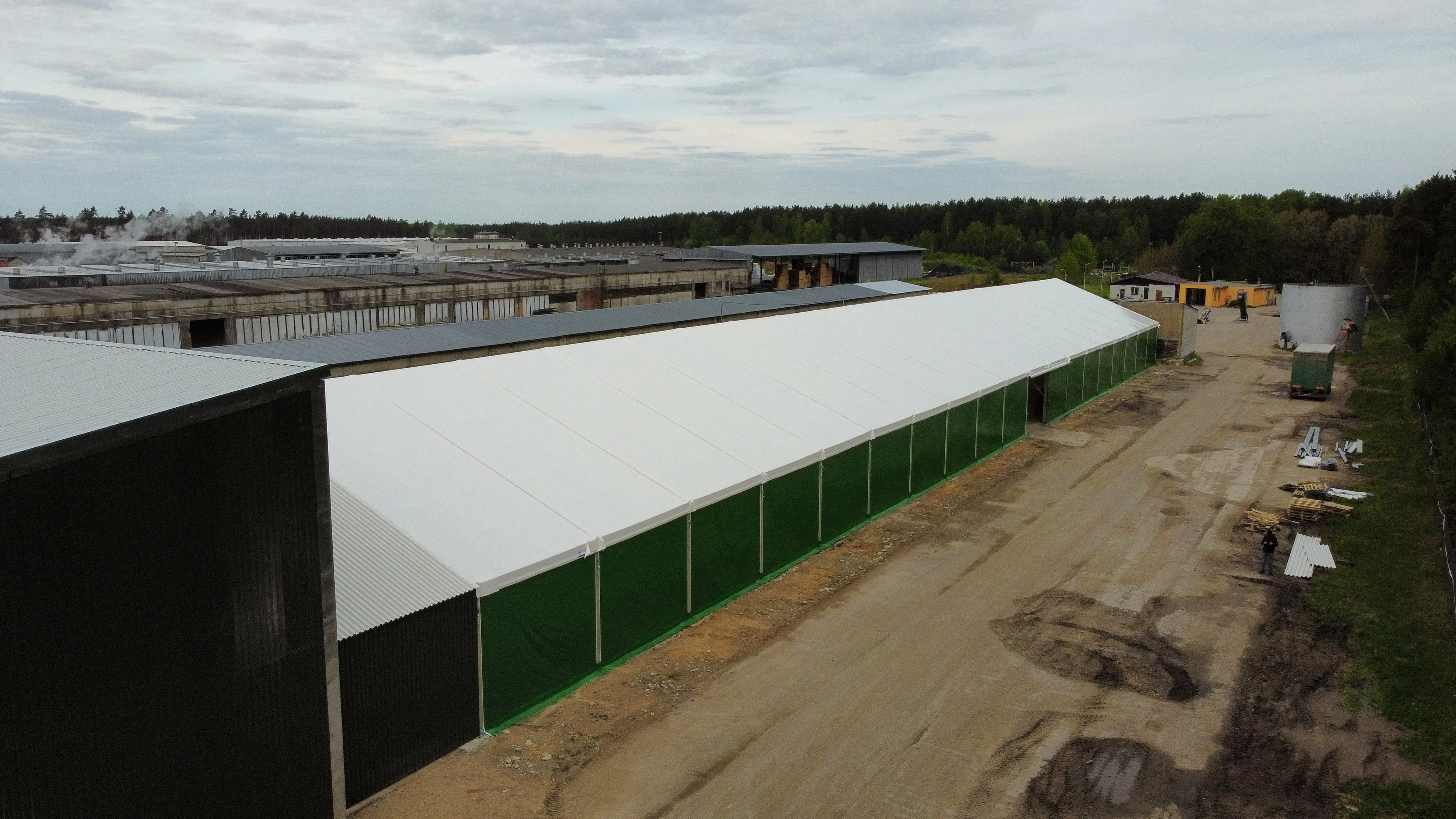Latgranulas 20 × 100 m angārs ar zaļām PVC sienām un baltu jumtu no gaisa